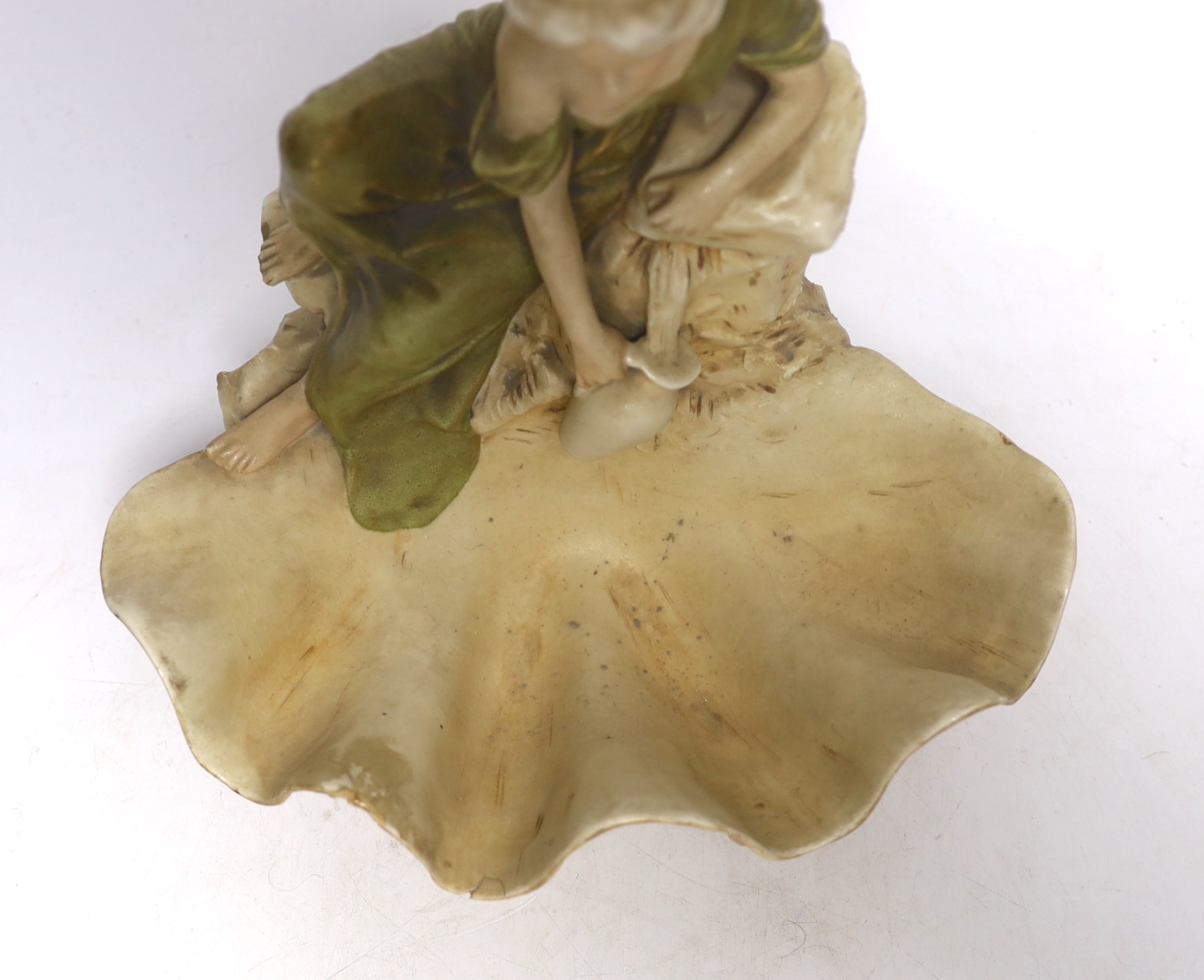A Royal Dux figure of a water carrier by a shell shaped pool, 26cm high
